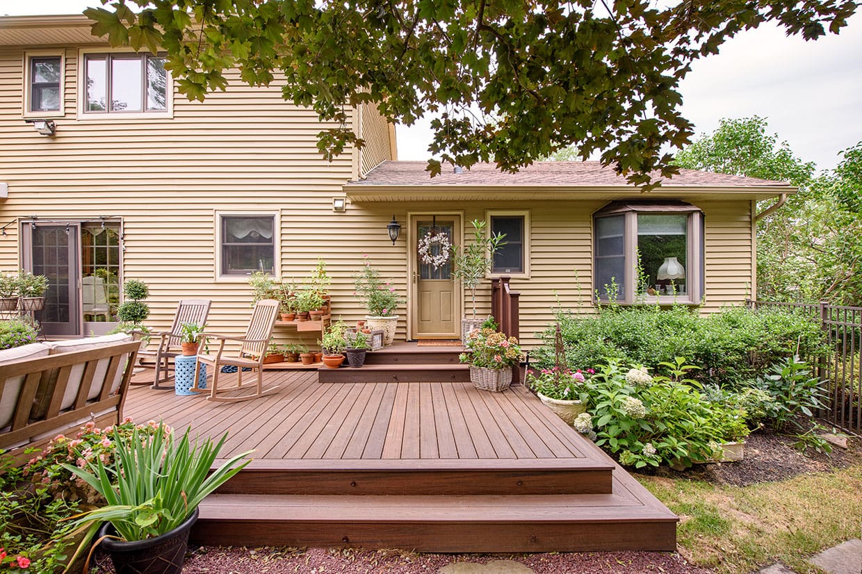 A picture of a finished ground level deck in the backyard of a house.