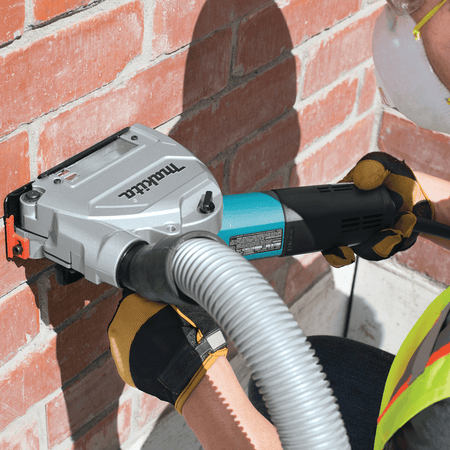 Person using a power tool against a brick wall