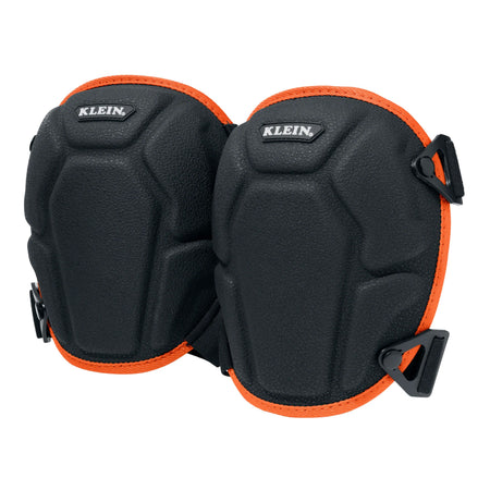 A pair of black Klein knee pads with bright orange trim and black plastic buckle closures, shown against a solid white background.