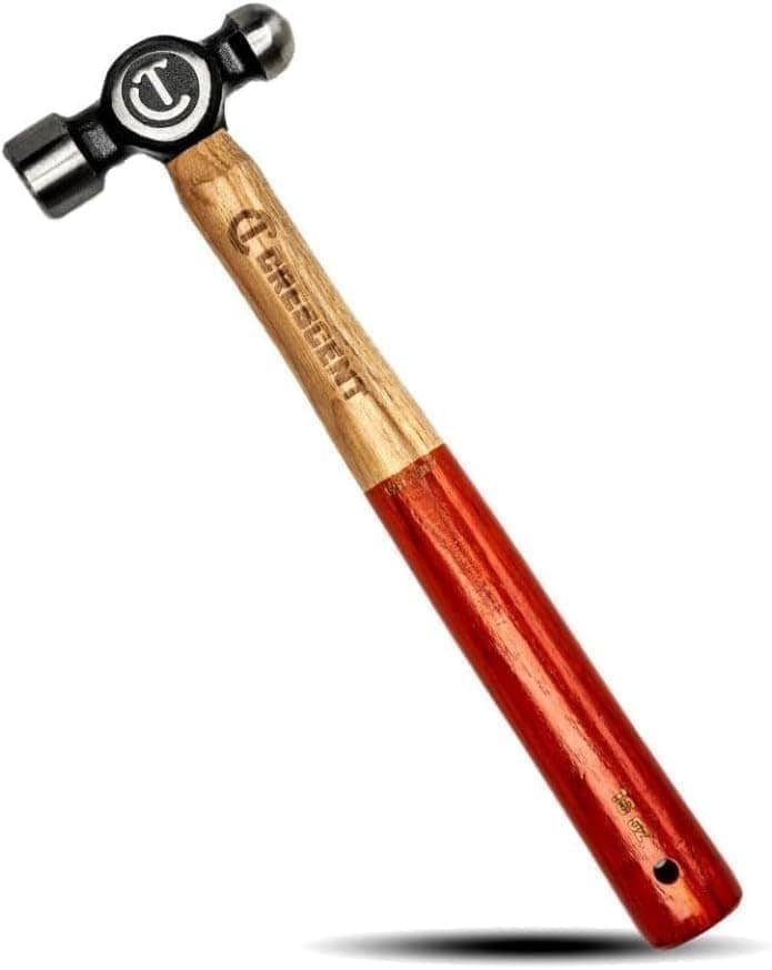 The image shows a Crescent ball pein hammer with a wooden handle that is red on the bottom portion and light brown towards the head. The hammerhead is black and features a flat striking face on one side and a rounded ball on the other, with the Crescent brand logo visible on the side of the head.