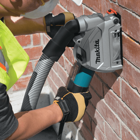 Person using a Makita power tool on a brick wall