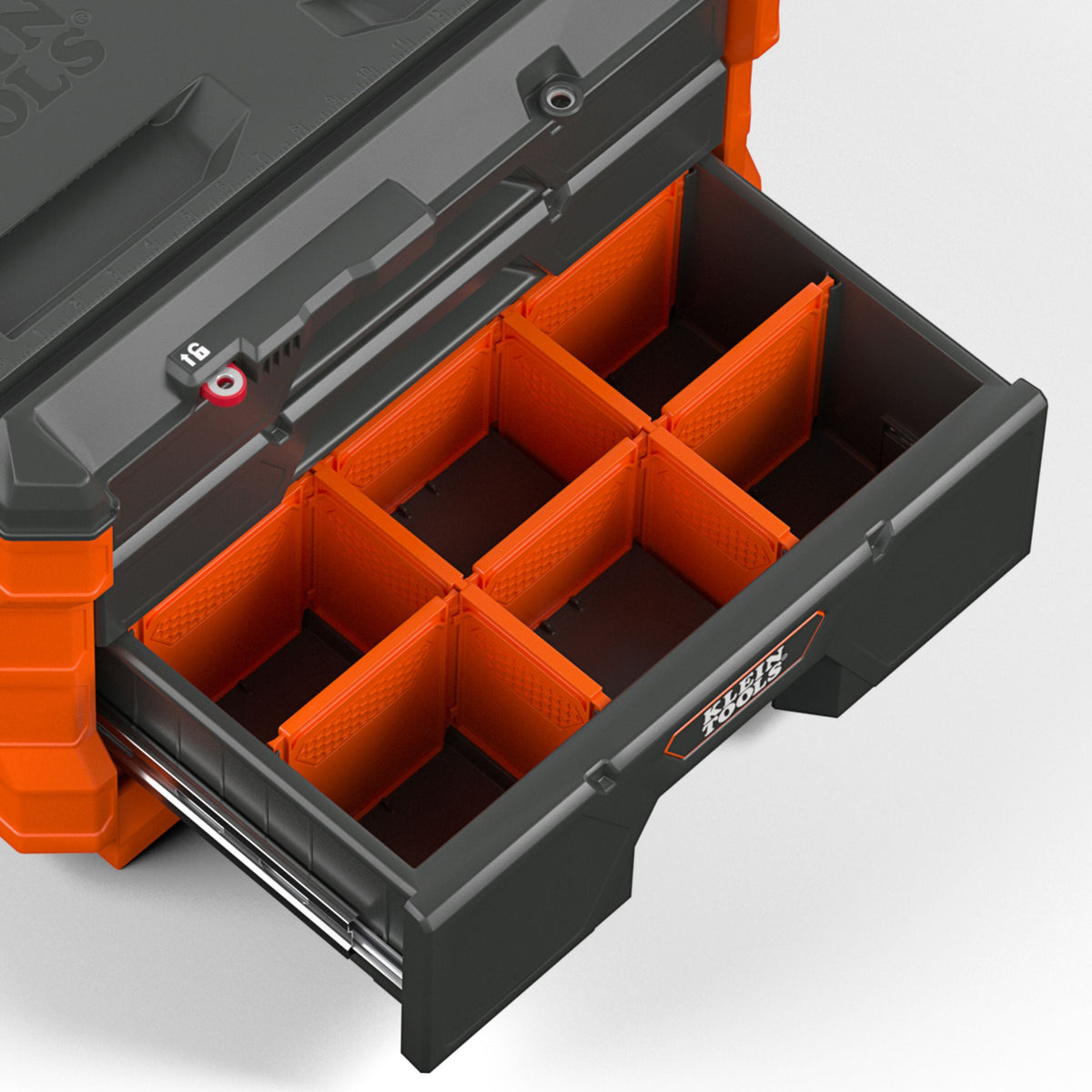 A close-up of a drawer organizer tool box with a partially pulled-out drawer. The organizer features bright orange interior dividers and a dark gray/black exterior with orange accents.