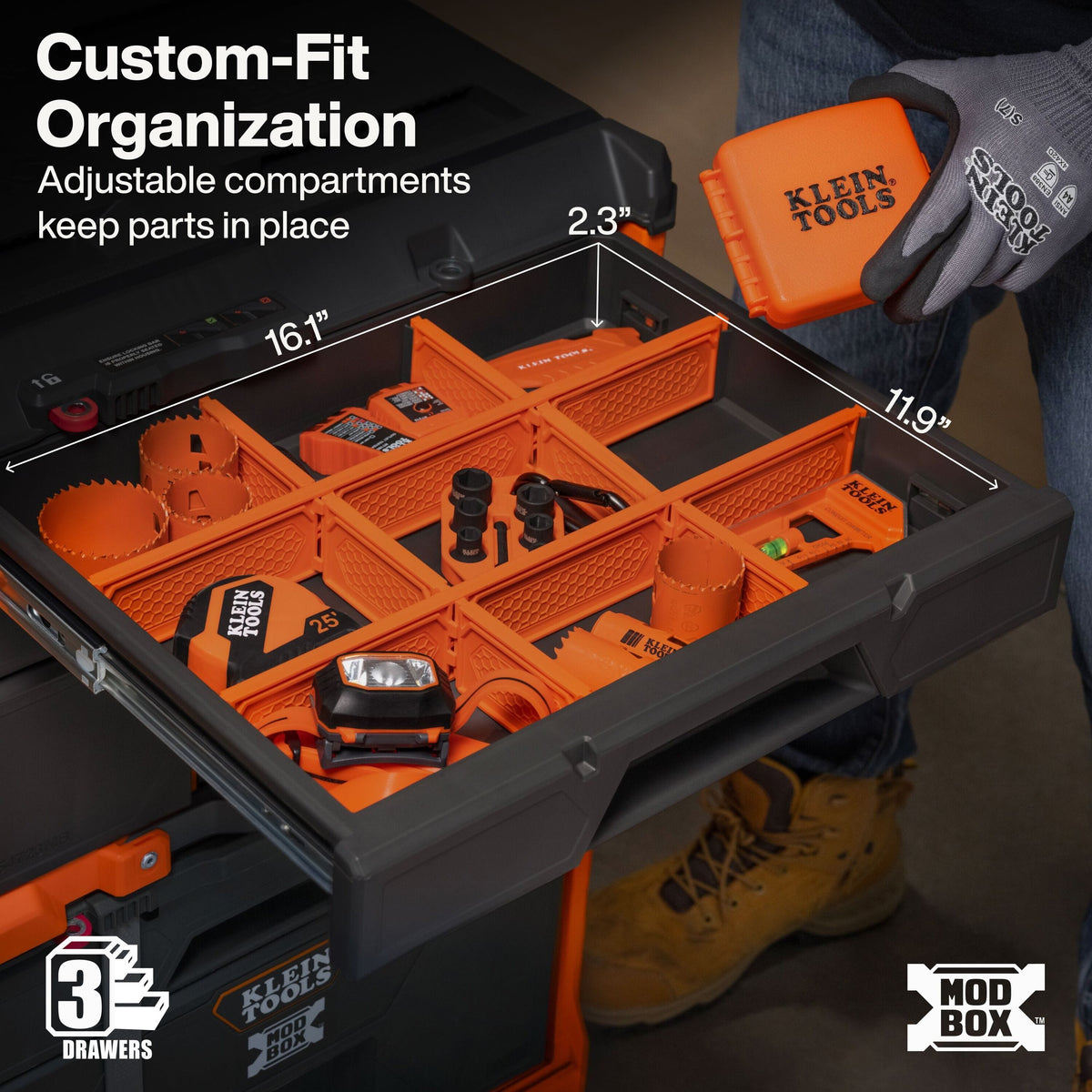 A black and orange Klein Tools modular storage box shown open with orange organizer trays and tools inside, with a gloved hand holding a matching orange drawer. Text highlights custom-fit organization and adjustable compartments, with dimensions marked on the box.