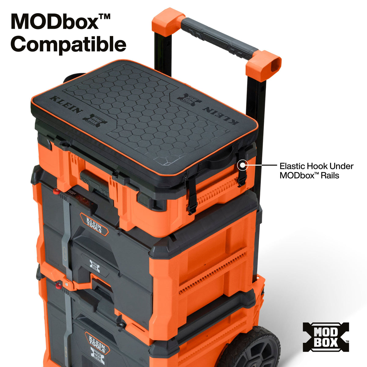 Stacked orange and black modular storage boxes on a white background with text reading 'MODbox Compatible' and a callout pointing to the elastic hook under the rails.