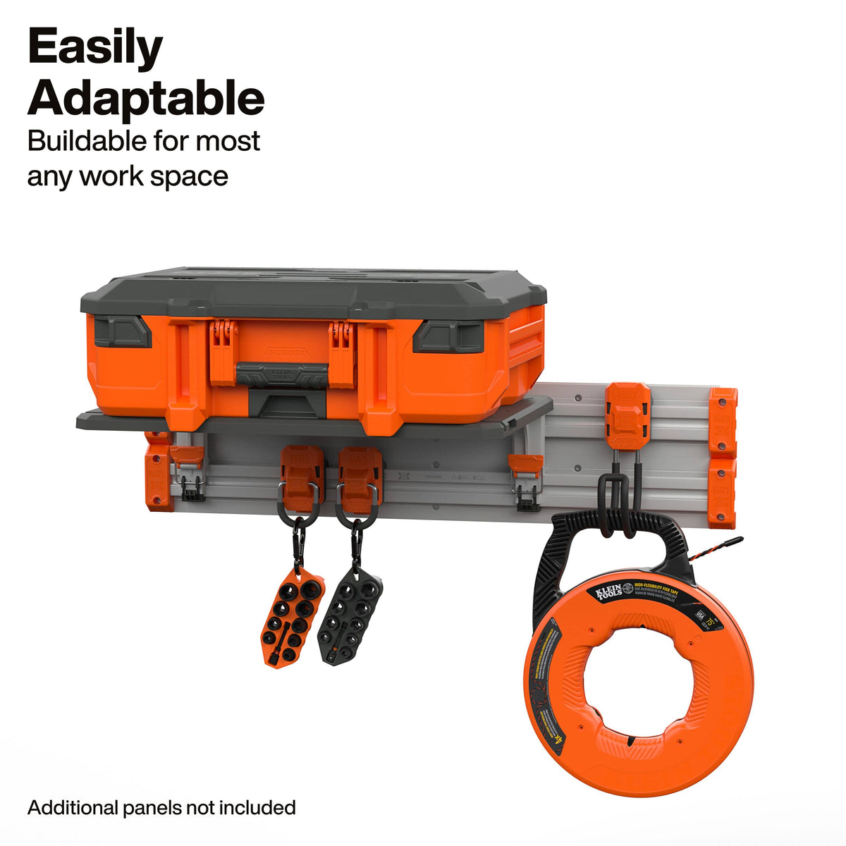 An orange and gray wall-mounted work space accessory kit with a hard case, mounting brackets, hanging hooks, and an orange circular reel, shown on a white background with text reading 'Easily Adaptable' and 'Buildable for most any work space.'.