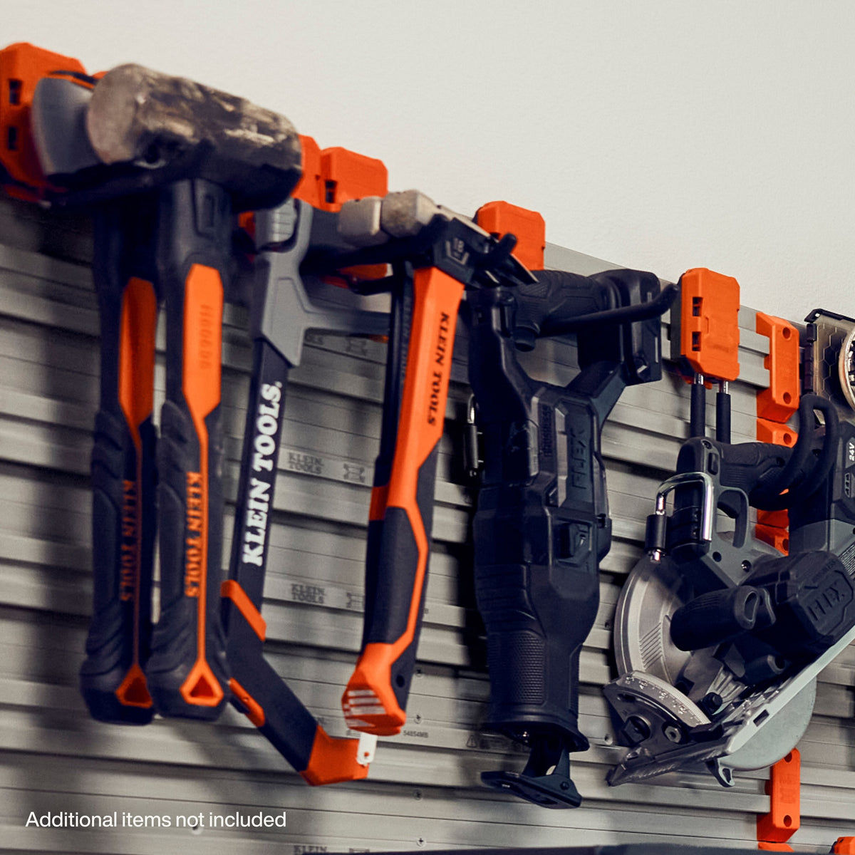 A wall-mounted tool organizer holding several Milwaukee tools, including a hammer, reciprocating saw, circular saw, and drill, with orange and black handles and orange wall hooks.