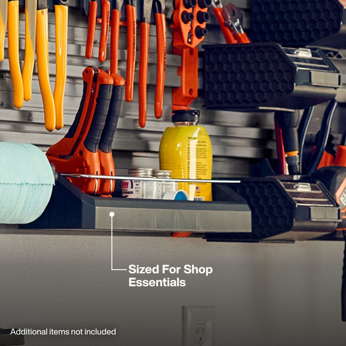 A gray plastic shelf tray on a garage organizer rack, shown holding small tools and bottles. White text reads 'Sized For Shop Essentials' and 'Additional Items not Included'.
