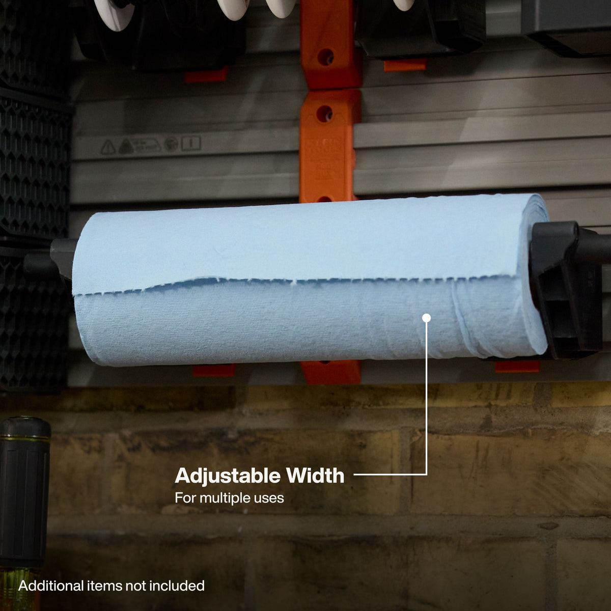 A roll of light blue paper towels or paper napkins mounted on a machine, with an overlay line pointing to the roll and the text 'Adjustable Width For multiple uses'.