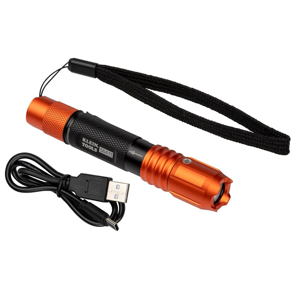 The image shows a small, handheld flashlight against a plain white background. The flashlight is mostly black with bright orange ends and has "KLEIN TOOLS 56411" printed on the side. Included with the flashlight are a black lanyard attached to one end and a separate black USB charging cable coiled nearby.