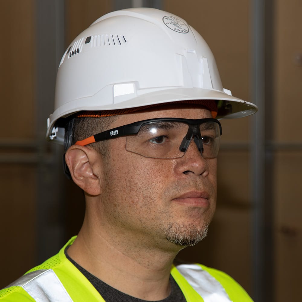 Person wearing a white hard hat and safety glasses with a blurred background
