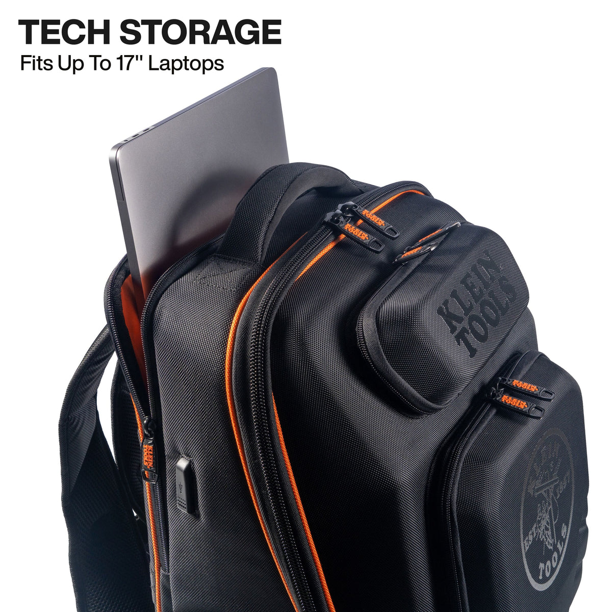 A black Klein Tools backpack with orange zipper accents, shown with a laptop partially inserted into the top storage pocket. Text in the upper left reads 'TECH STORAGE Fits Up To 17" Laptops'.
