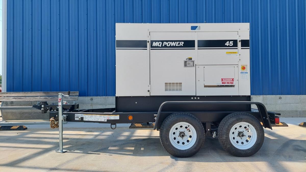Right side visual of the generator on the trailer, weth the big blue warehouse in the background.