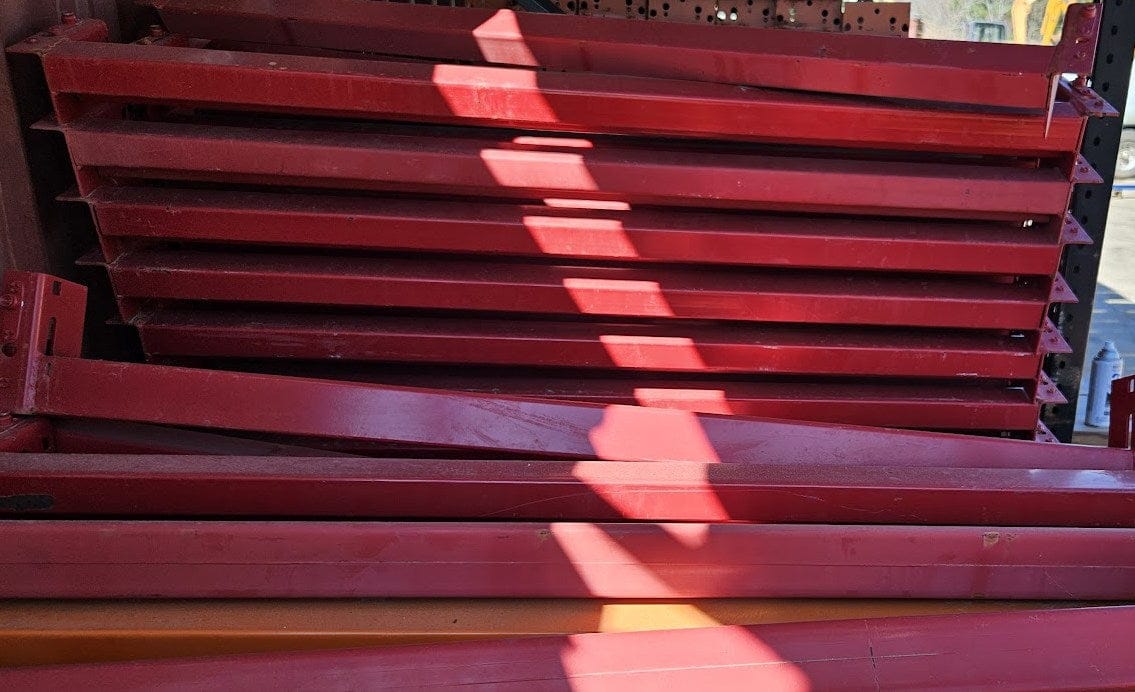 A stack of industrial teardrop pallet rack step beams in like new condition featuring a high-visibility safety red powder coat finish and standard 2.5-inch face height for heavy-duty 6-foot warehouse storage racking.