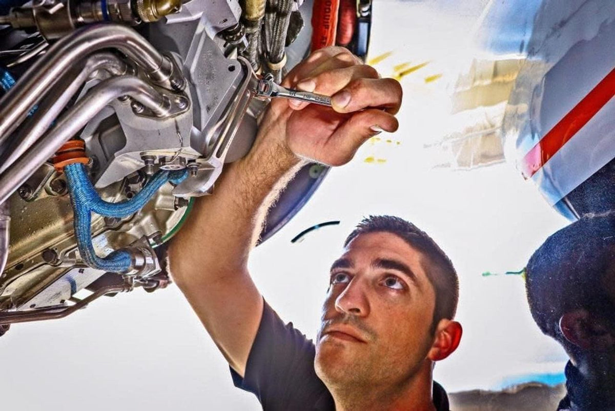 A mechanic looks up while using a small GEARWRENCH ratcheting wrench to tighten a fastener in the complex and tight confines of an aircraft engine.