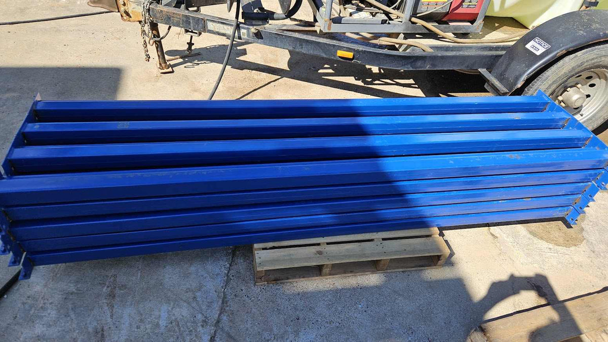 A stack of new industrial 8-foot teardrop pallet rack step beams on a wooden pallet featuring a professional blue powder-coated finish and a 4-inch face height for heavy-duty warehouse storage racking.