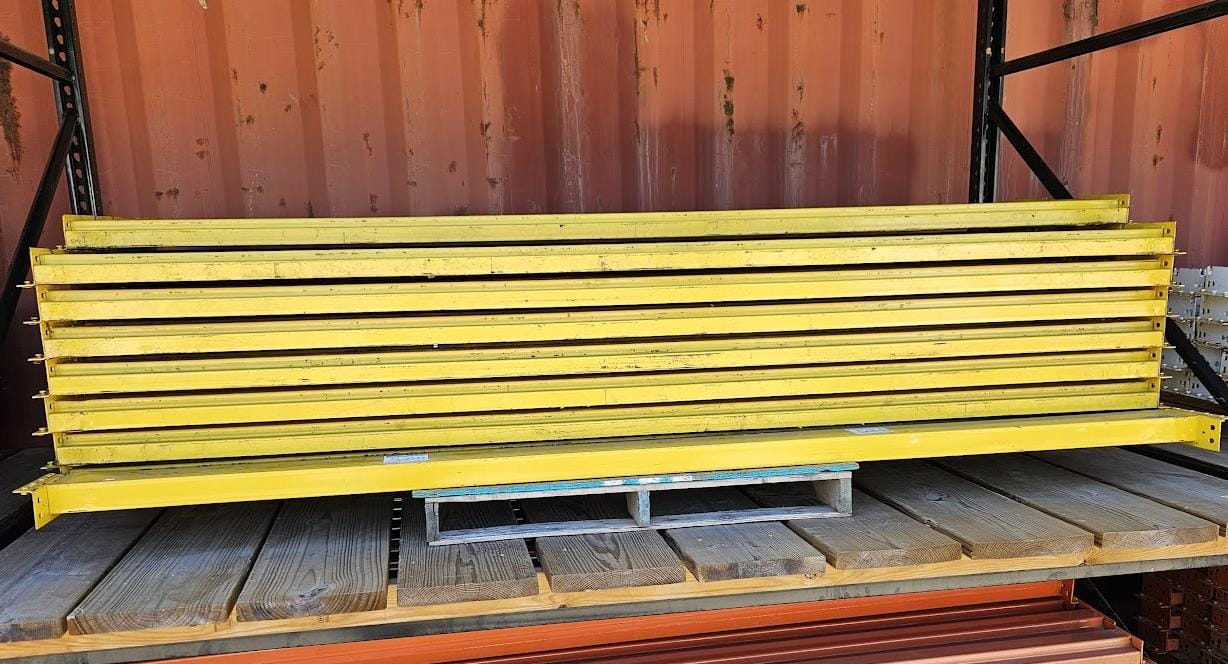 A stack of industrial 9-foot teardrop pallet rack step beams in used condition featuring a durable yellow finish and a 5-inch face height for heavy-duty warehouse storage racking.