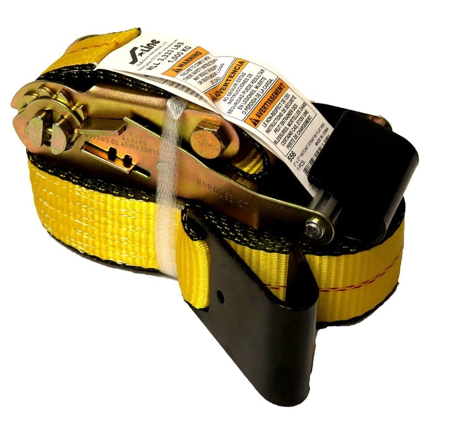 Coiled yellow ratchet tie-down strap with metal ratcheting mechanism and black protective sleeve. A white safety label with English and Spanish warnings and load specifications is attached to the strap
