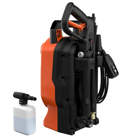 A compact BLACK+DECKER pressure washer with orange and black casing, built-in carry handle, hose reel, and mounted spray gun. A separate soap bottle attachment is placed beside the unit.