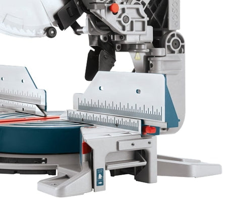 Detailed view of the left side of the saw base featuring the tall sliding fence for material support and the integrated expanding base extension for long workpieces