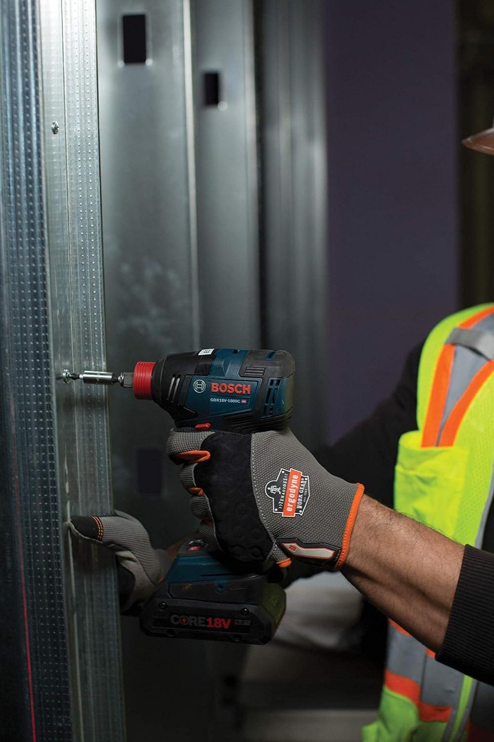 Worker wearing safety gear operating a Bosch GDX18V‑1800C reconditioned 18V brushless impact driver to fasten a screw into a metal stud, highlighting high‑efficiency fastening and professional‑grade tool control.