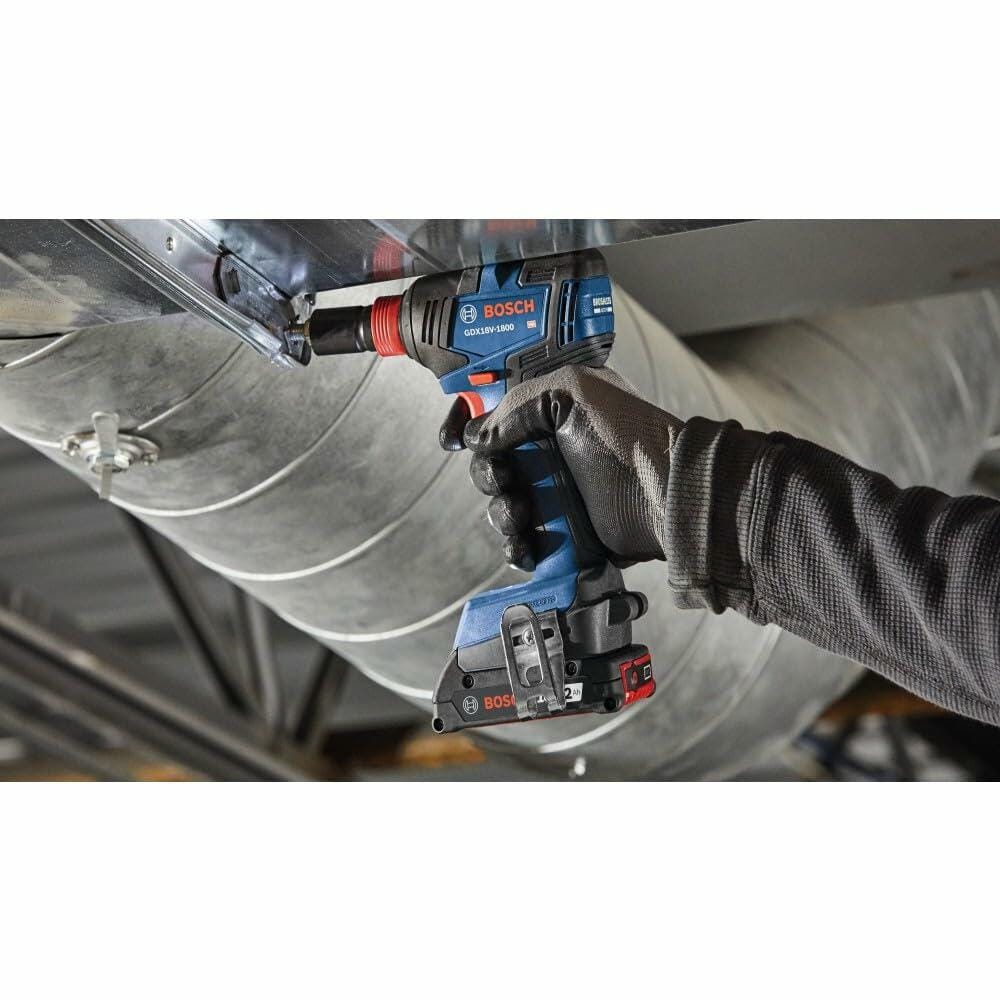 Bosch CORE18V brushless impact driver being used to fasten a large bolt into a wooden frame. The user wears a glove and plaid shirt, demonstrating the tool’s torque and control on a construction site.