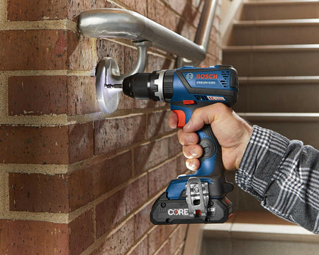 Person using a Bosch GSR18V-535C cordless drill to install a metal handrail bracket into a brick wall. Drill is equipped with a CORE18V battery. Scene highlights tool’s capability for drilling into metal and masonry surfaces during stairway construction.