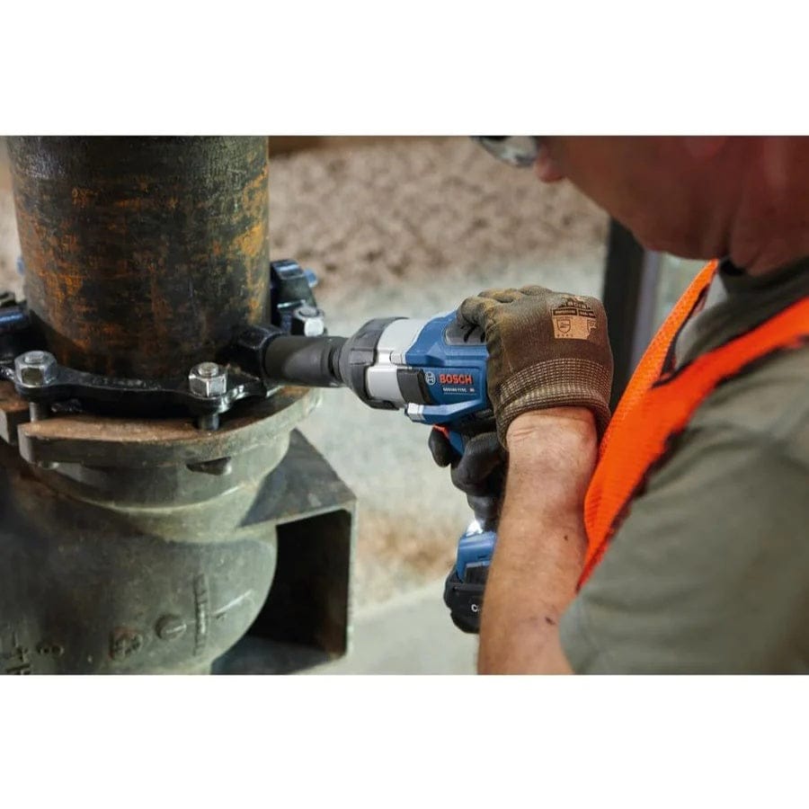 A worker uses the Bosch GDS18V-770CN impact wrench with a deep socket to tighten a large bolt on a heavy-duty, rusty pipe flange.