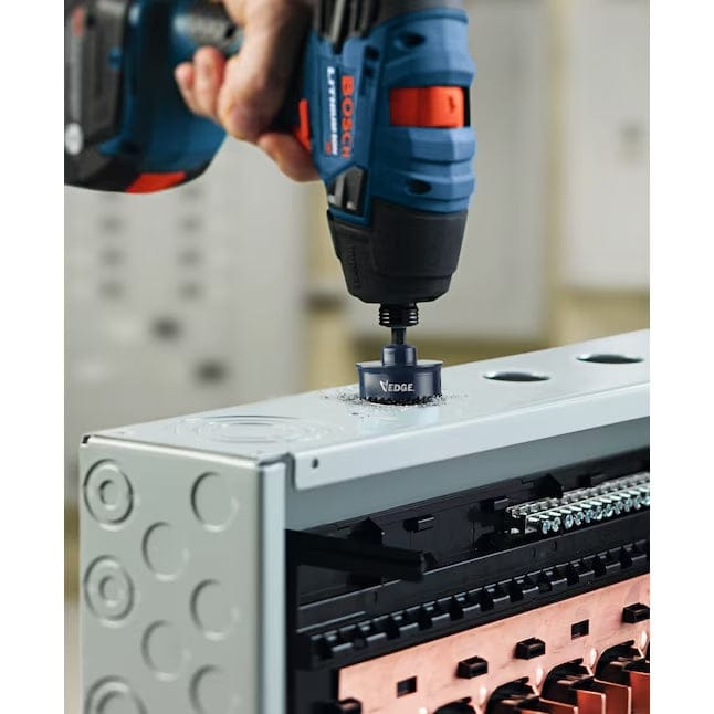 Person using Bosch cordless drill with HTW118 hole saw to cut a circular hole into a metal electrical panel, with copper bus bars and knockouts visible.