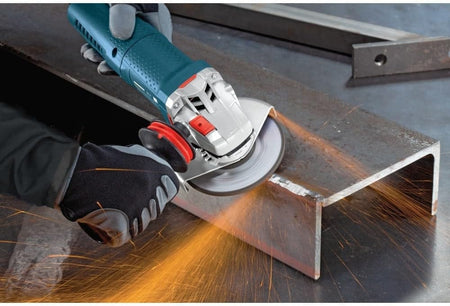 Person using an angle grinder to cut or grind a thick metal beam, with visible sparks and gloved hands holding the tool for stability.