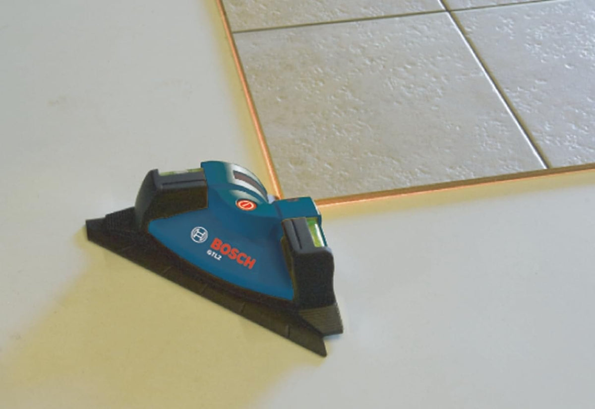 Bosch GPL2 laser level projecting a red laser line onto tile, used to align tile edges precisely during installation.