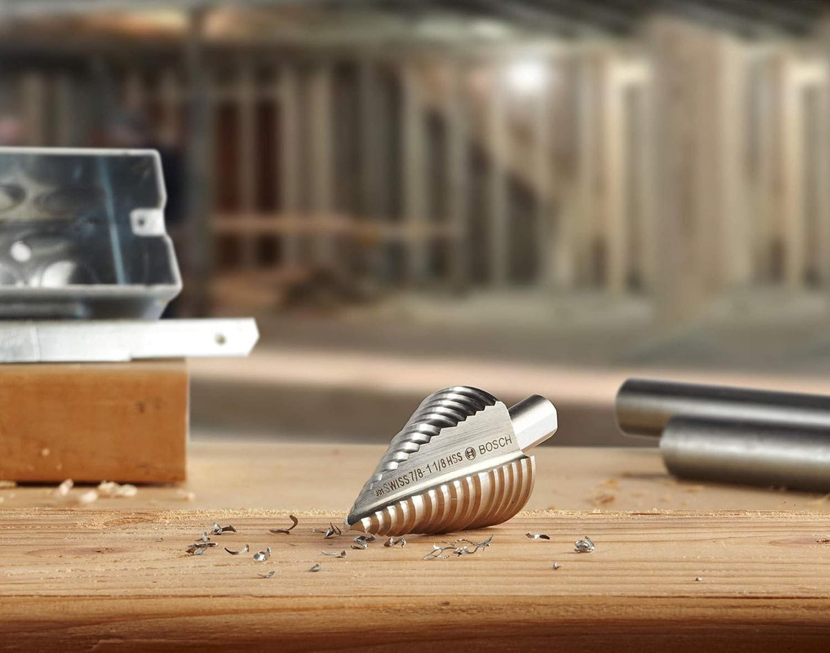 A Bosch HSS Turbo step drill bit rests on a workbench surrounded by metal shavings, with a construction site in the background.