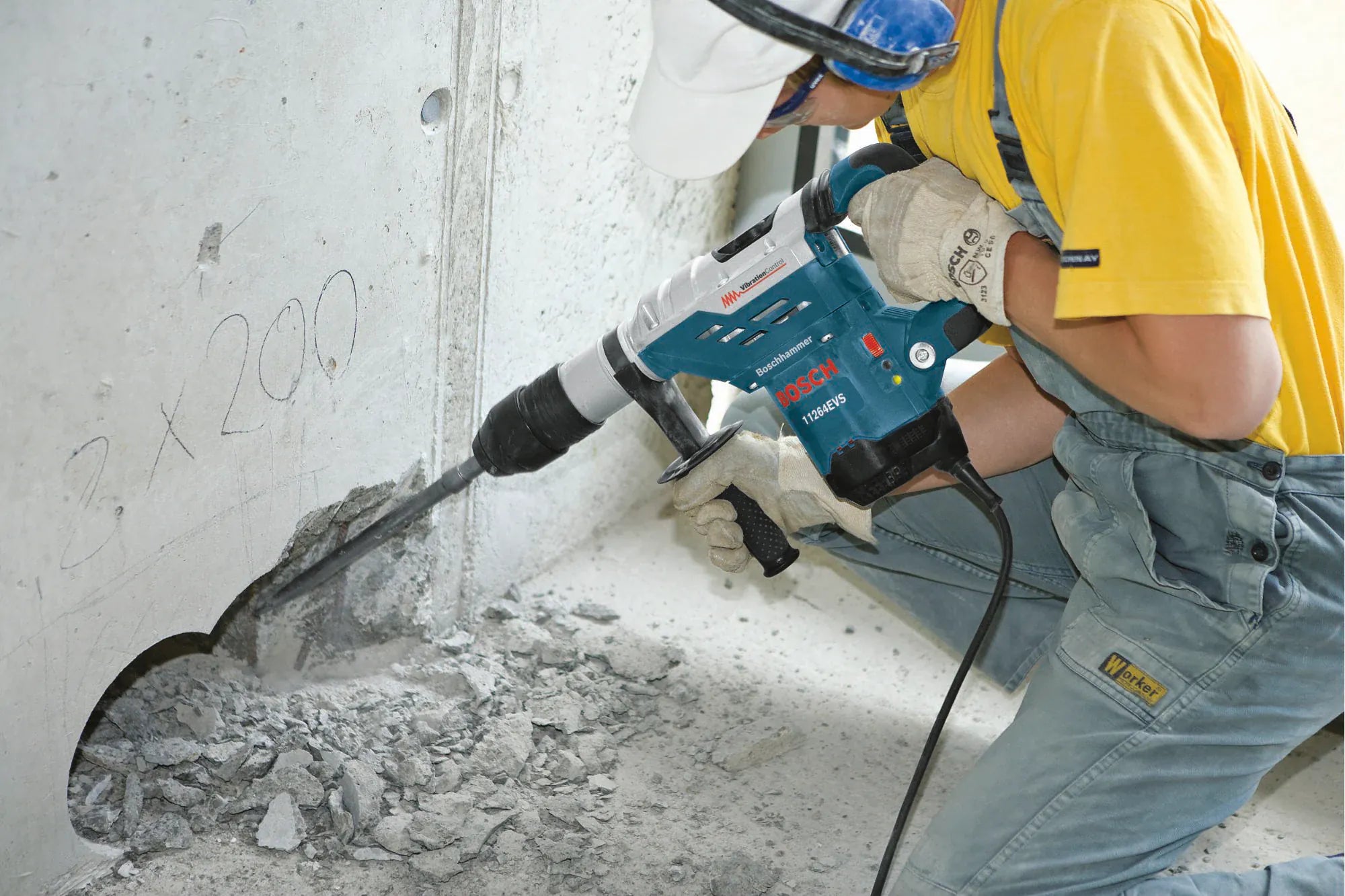 A worker using the Bosch 11264EVS combination hammer in hammer-only mode with a pointed chisel bit to perform heavy-duty demolition and material removal on a concrete structure.
