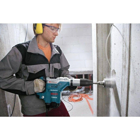 A professional using the combination hammer with a large diameter core bit to drill through a concrete wall.