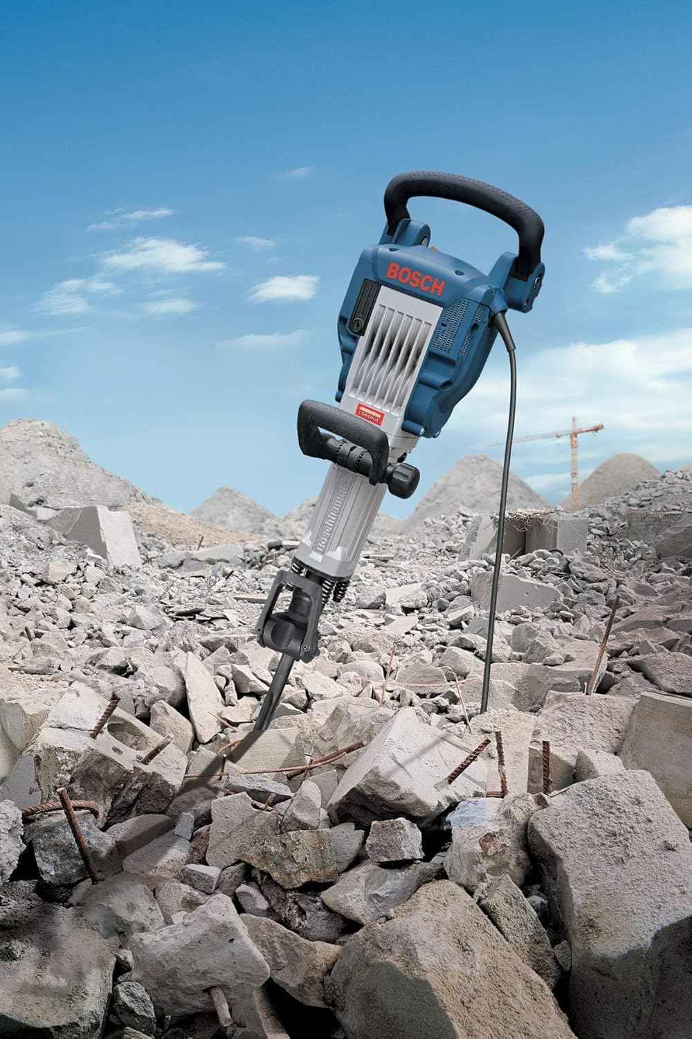 The Bosch 11335K breaker hammer standing upright in a pile of demolished concrete debris at a construction site.