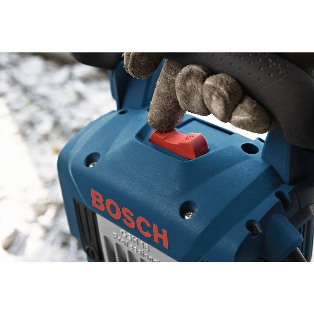 Close-up of a gloved hand sliding the red on/off switch located on top of the Bosch breaker hammer's housing.