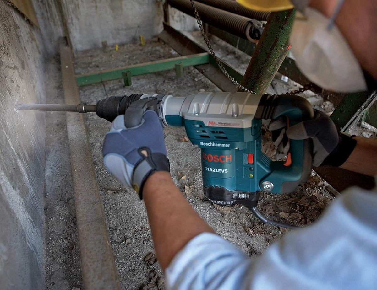An over-the-shoulder view of a worker using the Bosch 11321EVS hammer to chisel horizontally into a concrete wall.