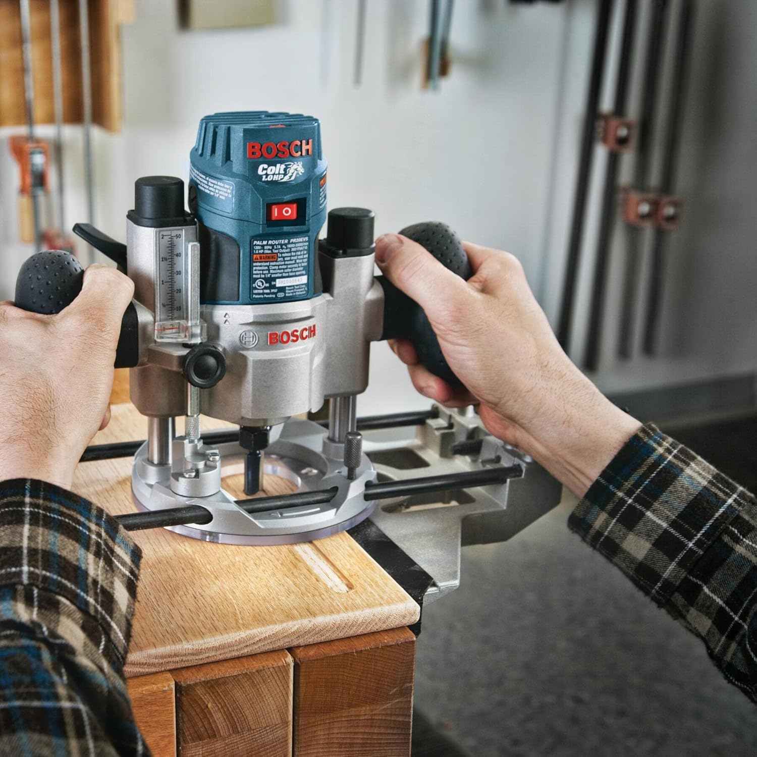 Action shot of a worker holding a Bosch router guiding it along a wooden board to create a profile.