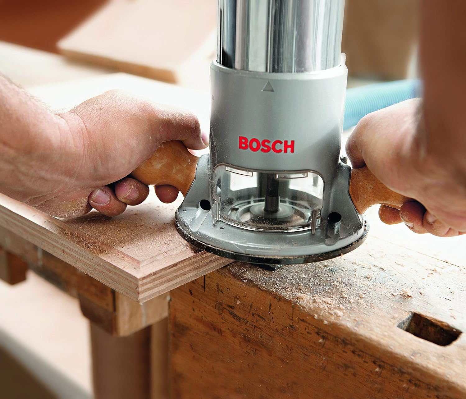 Close-up perspective of a woodworker’s hands gripping the hardwood handles of the Bosch 1617EVS router to perform a decorative edge routing pass on a thick piece of lumber.