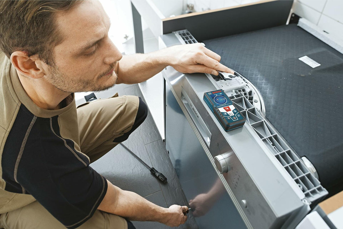Action shot of a contractor using the Bosch GLM50C laser measure to take precise measurements on a piece of cabinetry during installation or assembly
