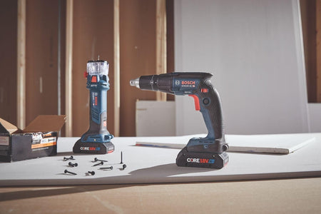 The Bosch GTB18V-45 screwgun and GCU18V-30 cut-out tool are shown standing on a piece of drywall on a workbench, with drywall screws scattered nearby and a wood-framed wall in the background.