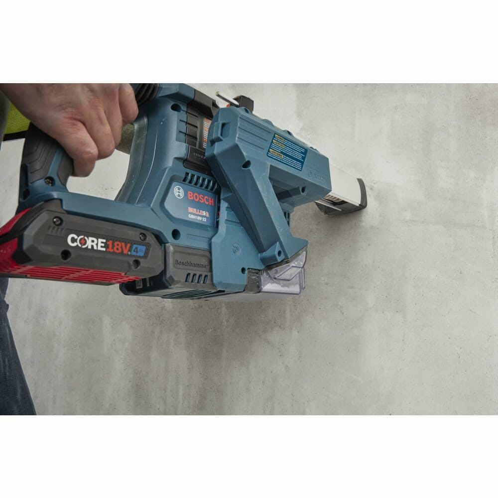 Close-up of a worker using the Bosch 18V Bulldog Rotary Hammer in hammer-only mode with a dust extractor attachment, chipping masonry or tile off a wall, demonstrating compliance and versatility.