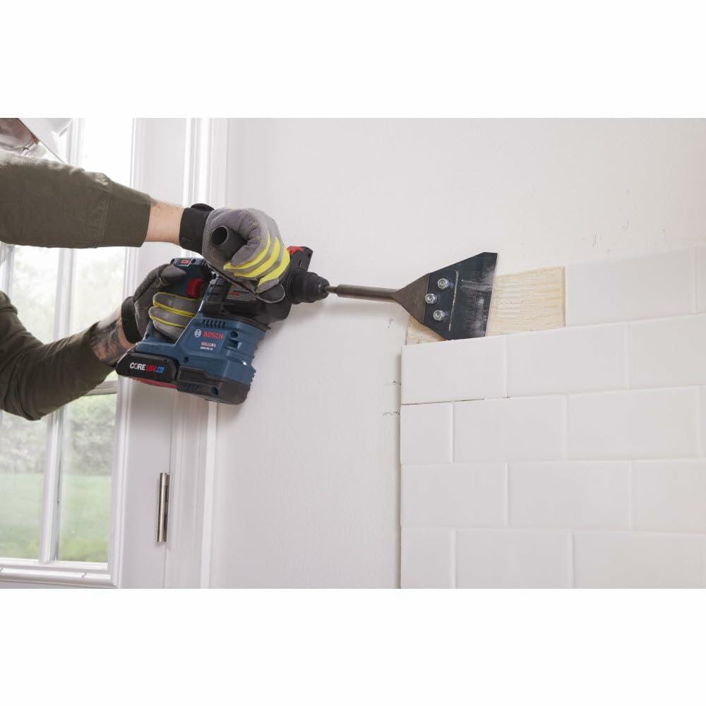 Worker using the Bosch 18V Bulldog Rotary Hammer fitted with a chisel attachment to remove subway tile from a kitchen wall, demonstrating the tool's hammer-only demolition capability.