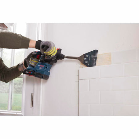 Worker using the Bosch 18V Bulldog Rotary Hammer fitted with a chisel attachment to remove subway tile from a kitchen wall, demonstrating the tool's hammer-only demolition capability.