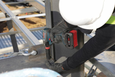 Construction worker using a Bosch 18V CORE18V‑powered impact tool to fasten a structural steel beam, demonstrating high‑torque fastening strength, rugged jobsite durability, and reliable performance for heavy‑duty steel assembly work.