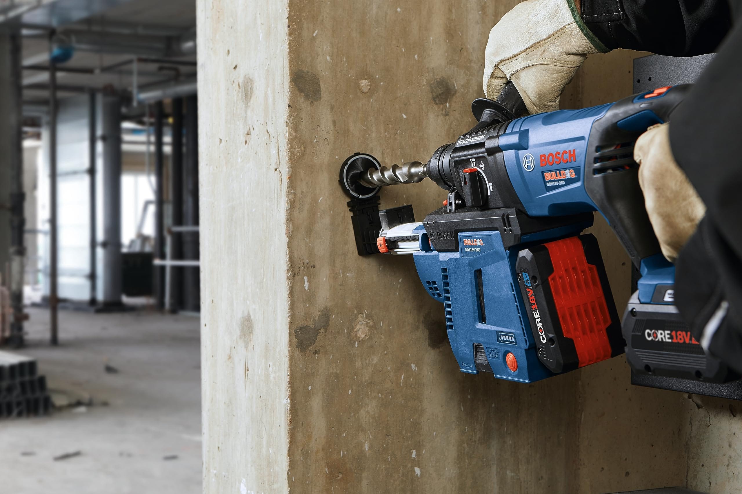 Action shot showing the Bosch rotary hammer drilling into a concrete column, featuring the tool paired with the optional GDE18V-26D cordless dust extractor for dust collection