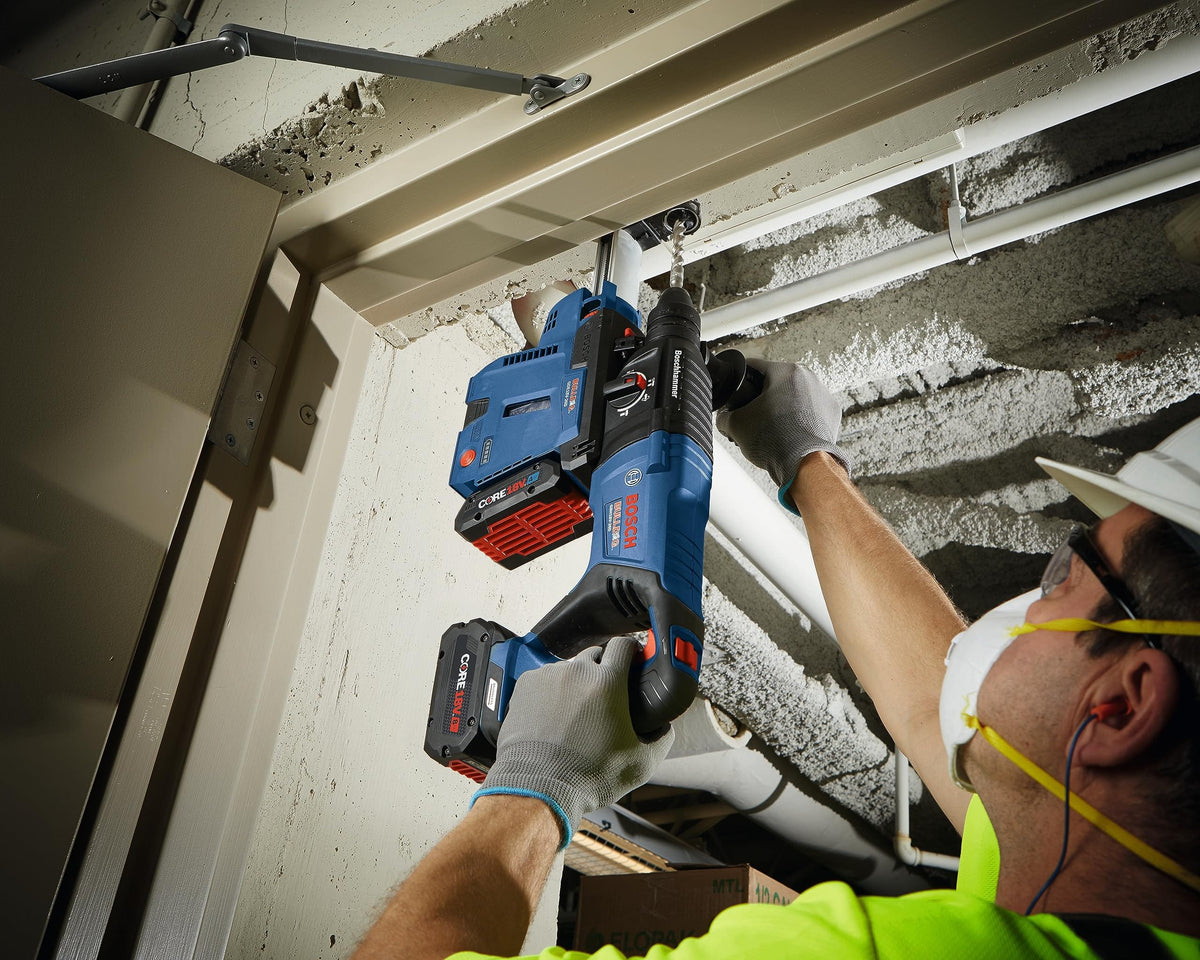 Action shot of a construction worker using the Bosch GBH18V-26D rotary hammer for overhead concrete drilling into a ceiling, demonstrating the tool's performance in tight jobsite conditions