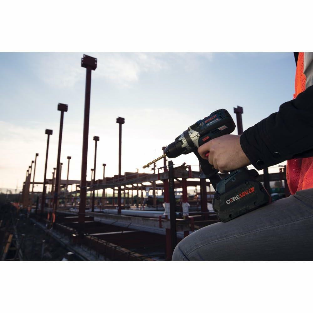 Person using a cordless drill on a construction site with a clear sky.