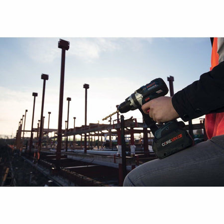Person using a cordless drill on a construction site with a clear sky.