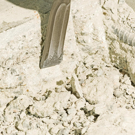A macro shot showing a Bosch self-sharpening flat viper chisel digging into concrete rubble and stone aggregate, illustrating effective material removal and low-friction line chiseling.