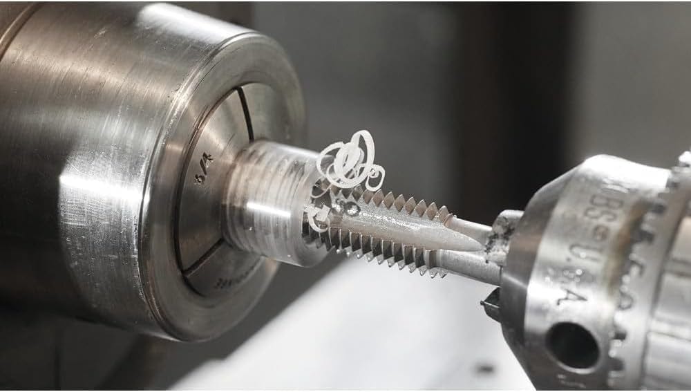 A close-up macro action shot of a Bosch tap in a lathe, cutting threads into a round metal workpiece.